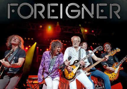 five musicians from the band Foreigner playing on-stage